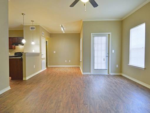 A spacious room with a ceiling fan and hardwood flooring.