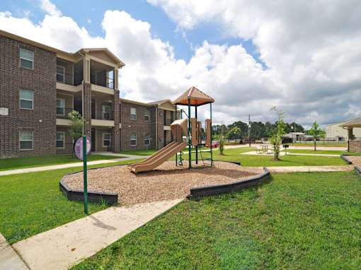 A playground with a slide and a building in the background.