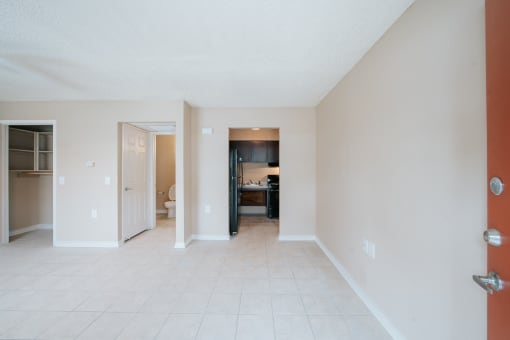 a living room with a tiled floor and a kitchen in the background
