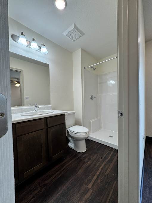 A bathroom with a toilet, sink, and mirror.