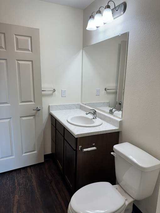 A white toilet sits in a bathroom next to a sink and mirror.