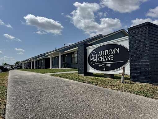 A sign for Autumn Chase stands in front of a building.