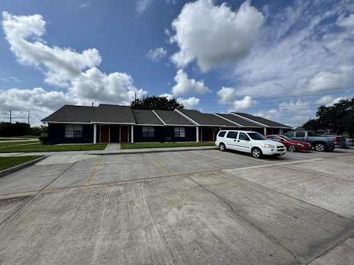 A white car is parked in a parking lot in front of a building.