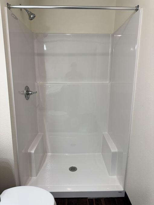 A white shower stall with a door and a shower head.