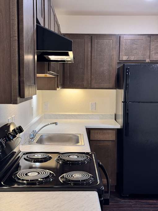 A kitchen with a black stove top oven and a black refrigerator.