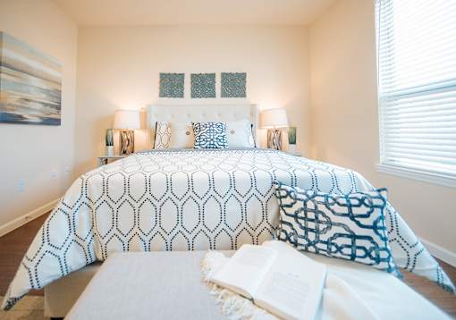 A bed with a white comforter and blue and white pillows.