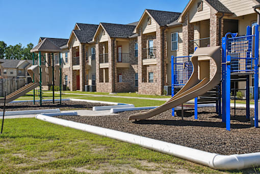 A playground with a slide and a building in the background.