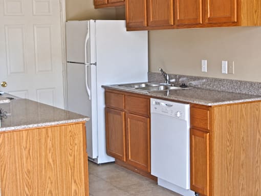 A white refrigerator stands in a kitchen with wooden cabinets.