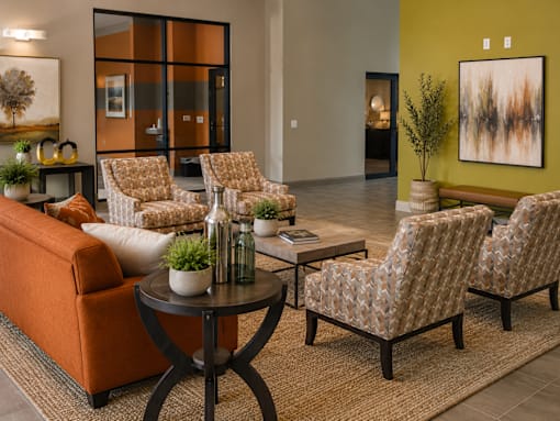 A living room with a sofa, two chairs, and a table with a plant on it.