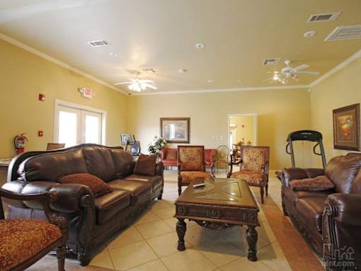 A living room with brown leather furniture and a ceiling fan.