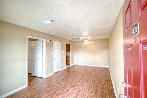 A room with a red door and a ceiling fan.