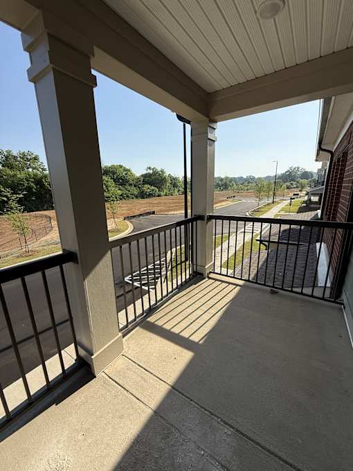 A balcony with a black railing and a view of a parking lot.