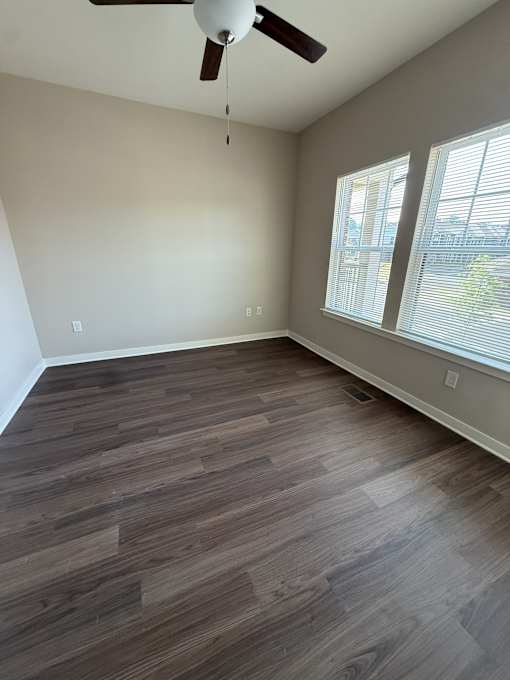 A room with a ceiling fan and wooden flooring.