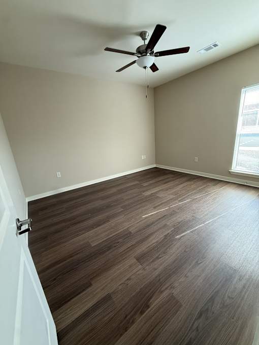A room with a ceiling fan and wooden flooring.