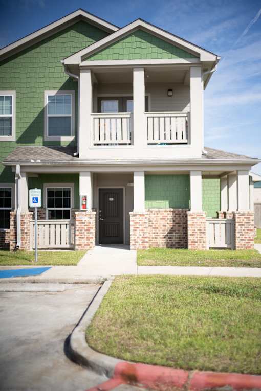 A green and white two story house with a black door.