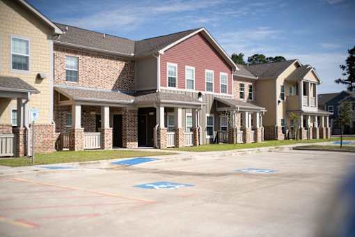 A parking lot in front of a building with a blue handicap sign painted on the pavement.