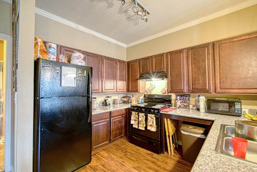 A black refrigerator stands in a kitchen with wooden cabinets.