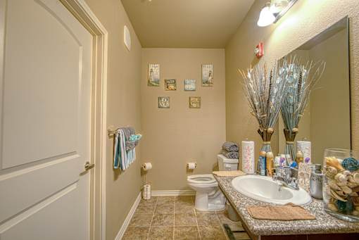 A bathroom with a toilet, sink, and a mirror.