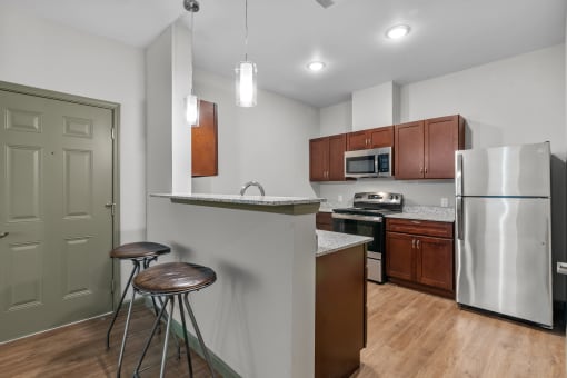 a kitchen with stainless steel appliances and a bar with two stools
