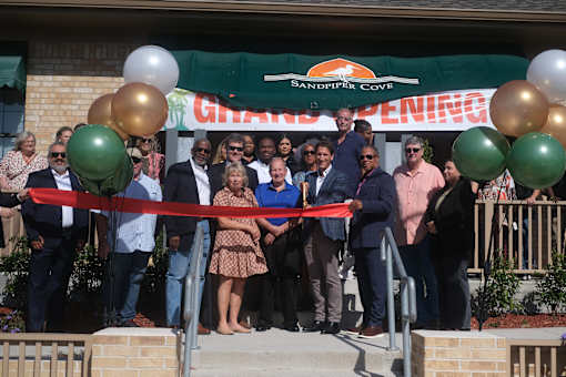 A group of people are gathered for a ribbon cutting ceremony.