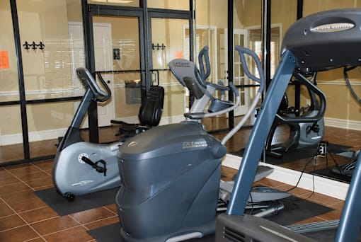 A gym with a treadmill, elliptical trainer and a stationary bike.