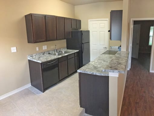 a kitchen with dark cabinets and granite counter tops