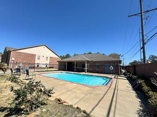 A pool in a backyard with a house in the background.