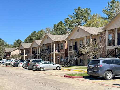 A row of houses with cars parked in front.