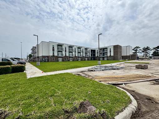 A modern apartment complex with a grassy area in front.
