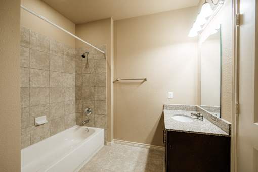 A bathroom with a white bathtub, a sink, and a mirror.