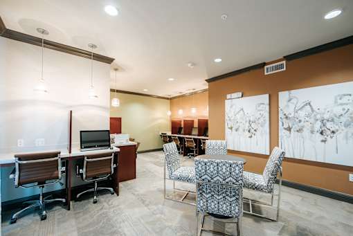 A room with a desk, chairs, and a painting on the wall.