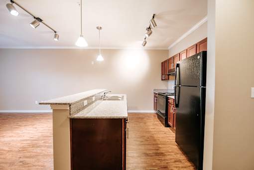 A kitchen with a black refrigerator and wooden floors.