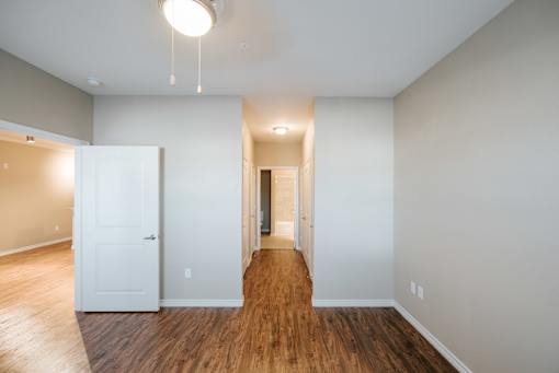 A room with a white door and a wooden floor.