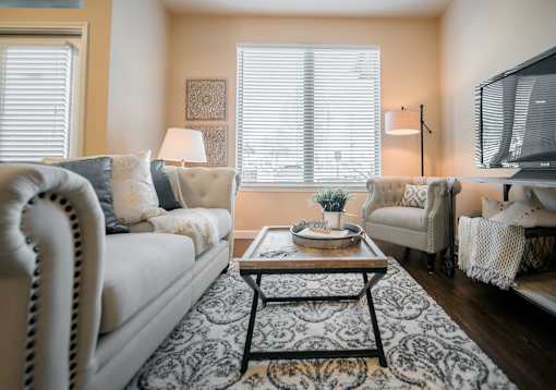 A living room with a white sofa, a coffee table, and a television.