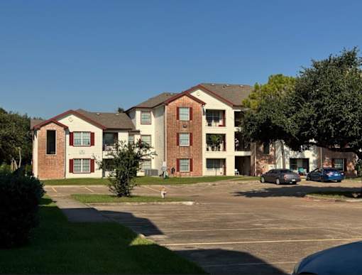 Apartment complex with a parking lot in front.