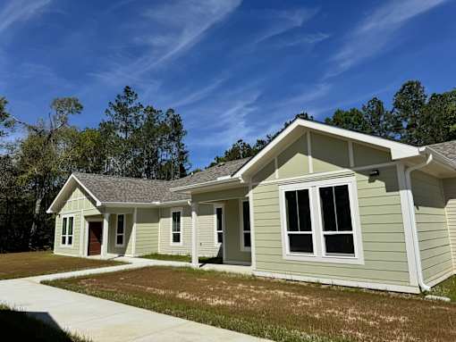 A house with a grey roof and white trim is shown with a clear blue sky in the background.