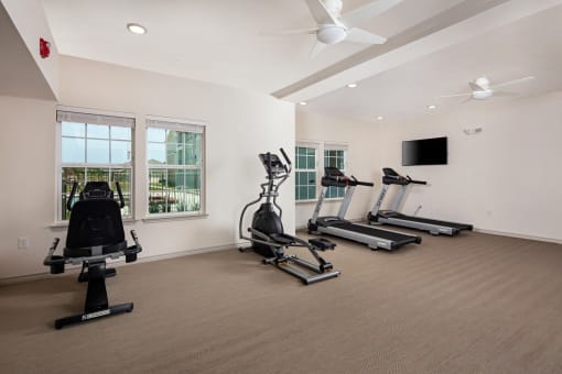 two treadmills and other exercise equipment in a room with windows