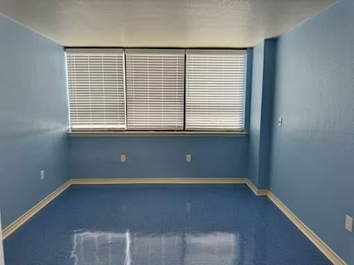 A room with blue walls and a window with blinds.