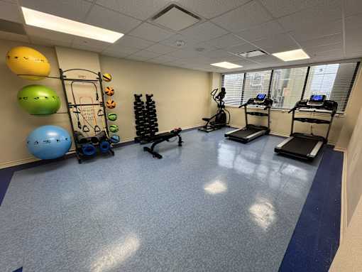 A gym room with a blue floor and exercise equipment.