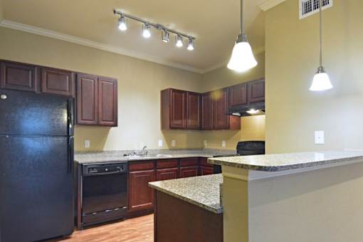 A kitchen with brown cabinets and a black refrigerator.