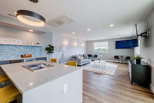 A modern kitchen with a large island and a living room with a couch and a TV.