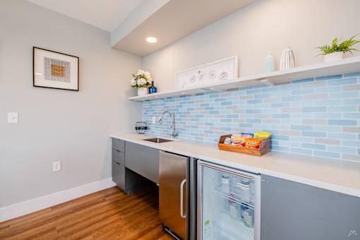 A kitchen with a blue tile backsplash and a stainless steel refrigerator.