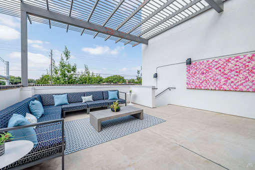 A patio with a blue couch and a table with a vase of flowers on it.