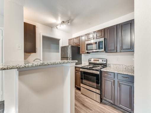 A kitchen with dark brown cabinets and stainless steel appliances.