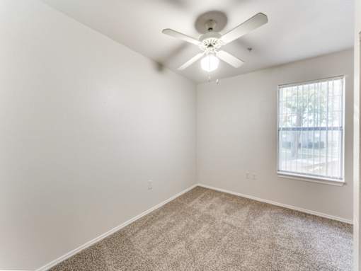 A room with a ceiling fan and carpeted floor.
