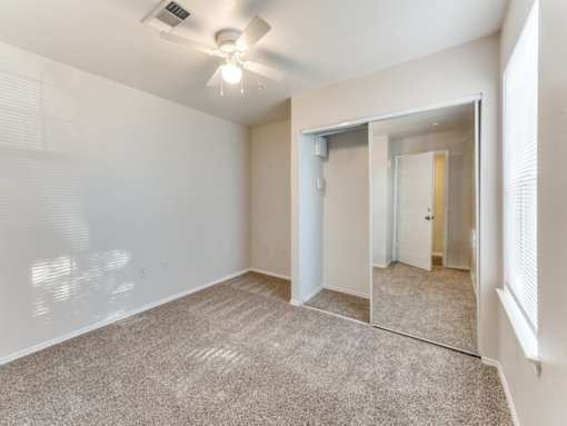 A room with a carpeted floor and a ceiling fan.