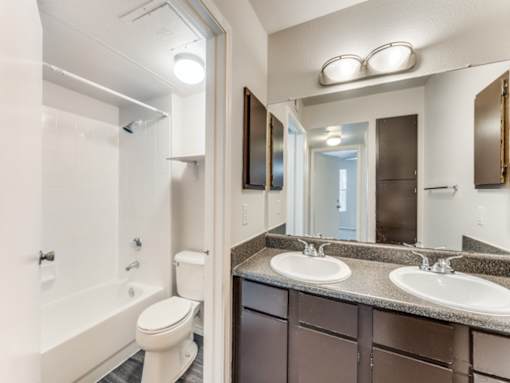 A bathroom with a toilet, sink, and mirror.