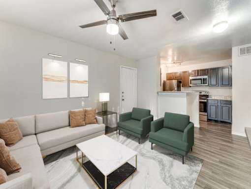 A living room with a white couch, green chairs, and a coffee table.