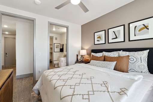Apartment bedroom with ceiling fan, patterned bedding and neutral decor