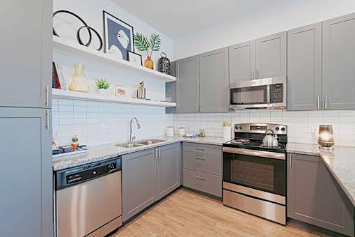 A modern kitchen with stainless steel appliances and wooden flooring.